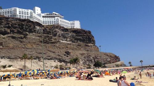 Un grupo de personas en una playa con un edificio. en Habitacion Puerto Rico, en Puerto Rico de Gran Canaria