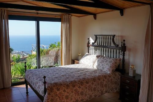 a bedroom with a bed with a view of the ocean at Ocean View Cottage in Ponta do Pargo