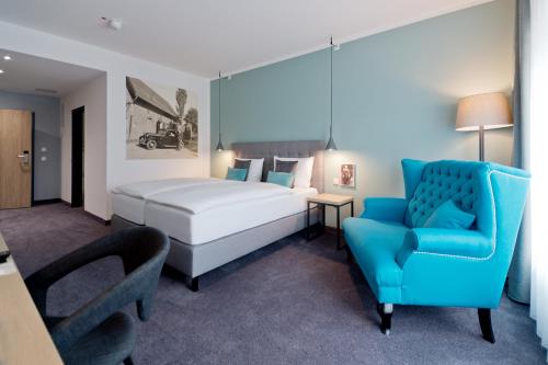 Niederzier的住宿－伯格奧本多爾夫酒店，一间卧室配有一张床和一张蓝色椅子