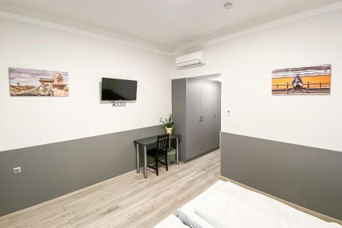 Zimmer mit weißen Wänden und einem TV an der Wand in der Unterkunft Dominik Panzió in Budapest