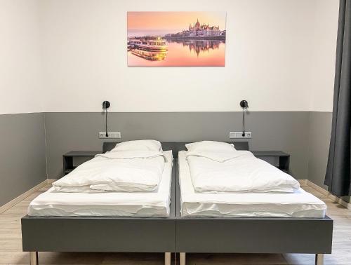 two beds in a room with a painting on the wall at Dominik Panzió in Budapest