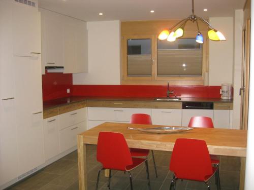 eine Küche mit einem Holztisch und roten Stühlen in der Unterkunft Pradin 1 in Arosa
