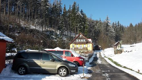 two cars parked in front of a house in the snow at Pension Vladimír in Janske Lazne