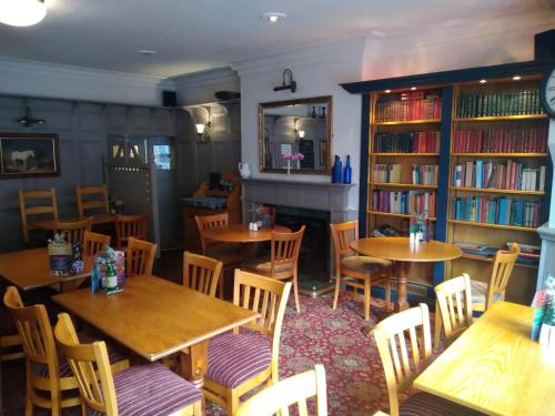 um restaurante com mesas, cadeiras e livros em The Wellington Hotel em Howden