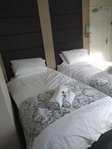 two beds with white sheets and towels on them at The Wellington Hotel in Howden