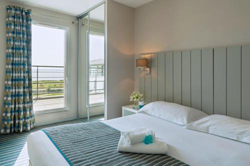 1 dormitorio con cama y ventana grande en Residence Thalasso Concarneau, en Concarneau