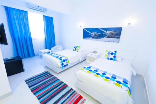 a white room with two beds and a couch at Lagoonie Lodge & Beach in Hurghada