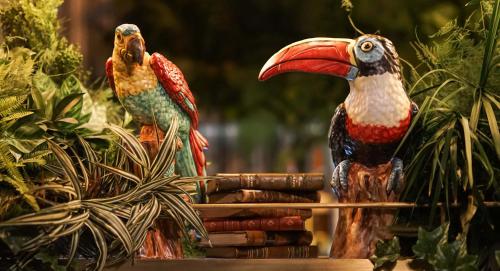 two colorful birds sitting on top of books at Hotel Casa Palacio María Luisa in Jerez de la Frontera