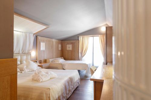 a hotel room with two beds and a window at Hotel Spinale in Madonna di Campiglio