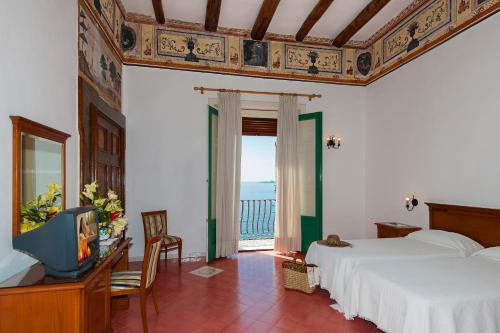 a bedroom with two beds and a television and a balcony at Albergo California in Positano