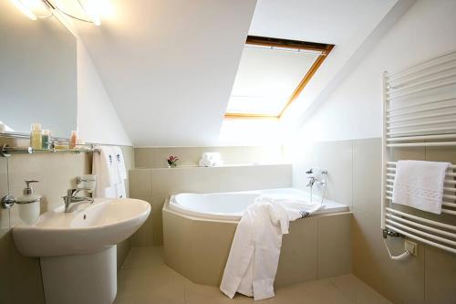 La salle de bains blanche est pourvue d'un lavabo et d'une baignoire. dans l'établissement Gourmet Hotel Villa Patriot, à Mariánské Lázně