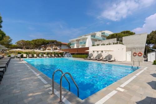 basen z krzesłami i budynek w obiekcie Park Hotel Ermitage Resort & Spa w mieście Lido di Jesolo