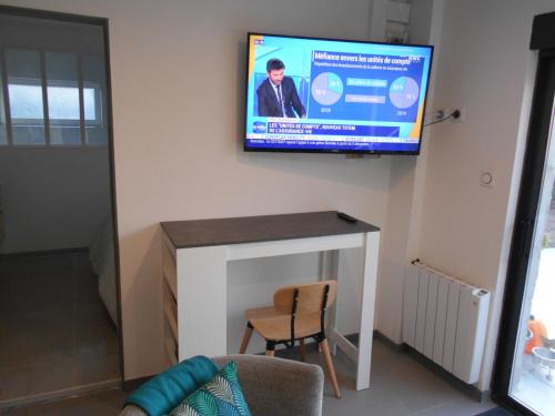 a tv on a wall with a table and a chair at 4MIN ORLEANS APPT 1CHB PLEIN AU CALME AVEC TERRASSE ET PARKING DEVANT in Saint-Jean-de-Braye