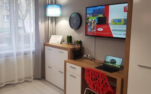 um quarto com uma secretária com um computador portátil e uma televisão em Arena Studio em Gliwice