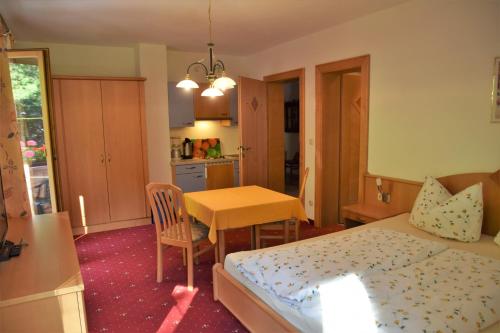 a bedroom with a bed and a table and a kitchen at Steglacher Hof in Mayrhofen