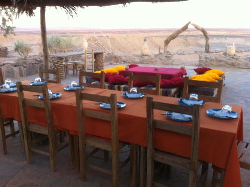a table with chairs and a table with a view of the desert at Maison Boutchrafine in Erfoud