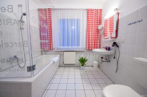 a bathroom with a tub and a toilet and a sink at Hotel Forsthaus Sellin in Ostseebad Sellin