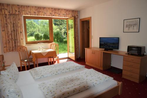 a bedroom with two beds and a desk and a television at Steglacher Hof in Mayrhofen