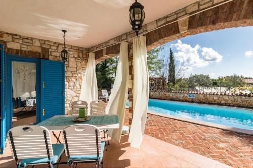 un patio con mesa y sillas junto a una piscina en Villa-Johanna, en Kaštelir