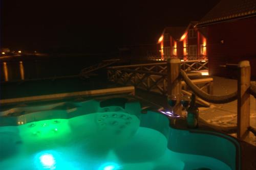 a jacuzzi tub at night with a house in the background at XLyngen in Nord-Lenangen