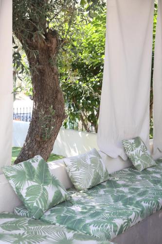 a couch with pillows sitting in front of a tree at Philoxenia Village Hotel-Studios in Pefkochori