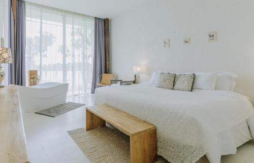 een witte slaapkamer met een groot bed en een bank bij White Wall Riverfront Hotel in Kamphaeng Phet