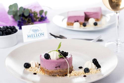 a piece of cake on a plate with blackberries and whipped cream at Mellon Country Inn Hotel in Omagh