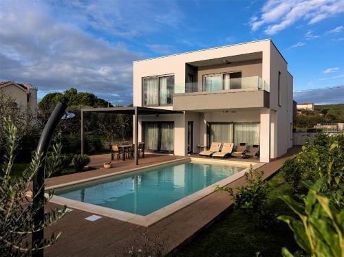 a house with a swimming pool in front of it at Villa Lu-Ma Beachfront with Heated Pool in Turanj