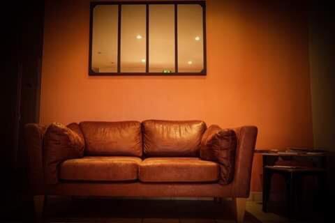 a brown leather couch in a room with a mirror at Hôtel Les Jardins du Lac in Autun