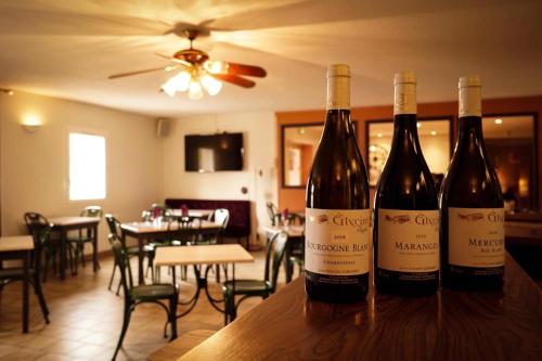 two bottles of wine sitting on a table in a restaurant at Hôtel Les Jardins du Lac in Autun