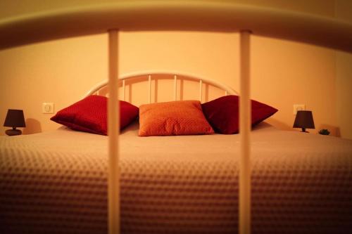 a bed with red and orange pillows on it at Hôtel Les Jardins du Lac in Autun
