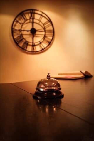 un reloj en una pared y un teléfono en una mesa en Hôtel Les Jardins du Lac, en Autun