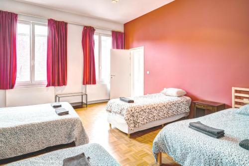 a room with two beds and red walls at Three Bedroom Marble Apartment in the Heart of Antwerp in Antwerp