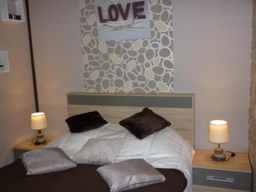 a bed with two pillows and a sign that says love at Villa Étienne in Le Mont-Dore