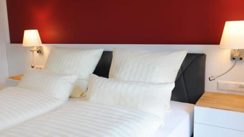1 cama con almohadas blancas y pared roja en Hotel Am Markt, en Heek