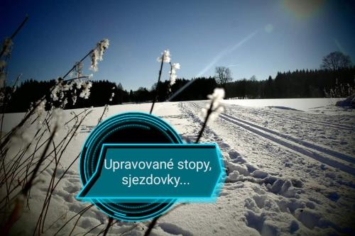 a sign sitting in the snow in a field at Penzion Poslední míle in Milovy