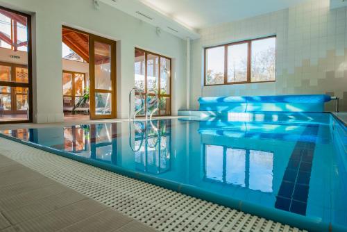 a large swimming pool with blue water in a house at Hotel Praděd Thamm in Zlaté Hory