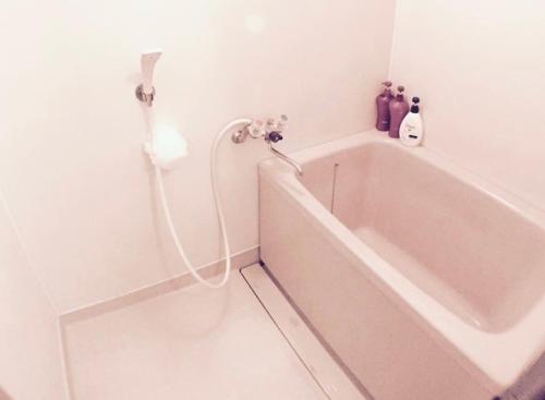 a white bath tub in a bathroom with a hose at 光アパートメント広島駅前 HIKARI Apartment Hiroshima Station in Hiroshima