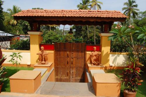 a gazebo with a wooden door and two statues at Martins Comfort in Betalbatim
