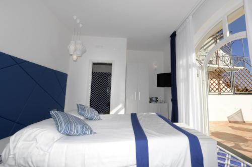 a bedroom with a white bed with blue pillows at Palazzo San Giovanni Amalfi Coast in Scala