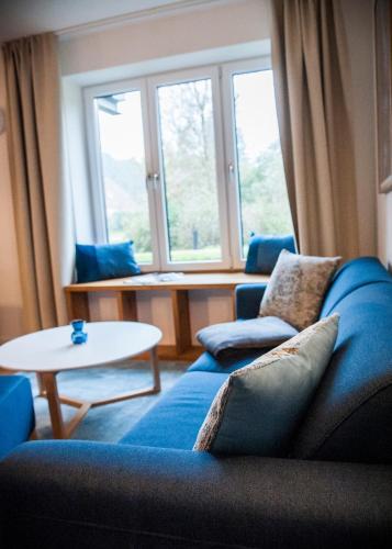 a living room with a blue couch and a table at Apartmenthaus Feldberg in Feldberg