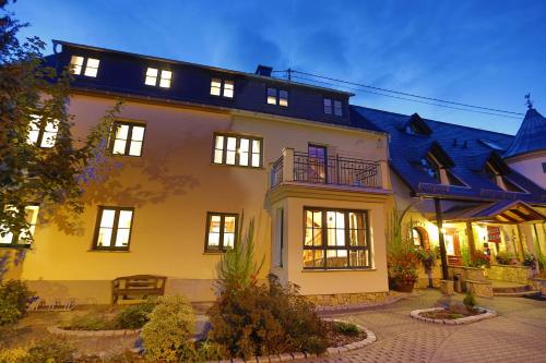a large yellow house with lights on at Landhotel Villa Moritz garni in Oberahr