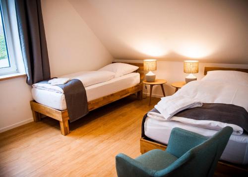 Cette chambre comprend 2 lits et une chaise. dans l'établissement Apartmenthaus Feldberg, à Feldberg