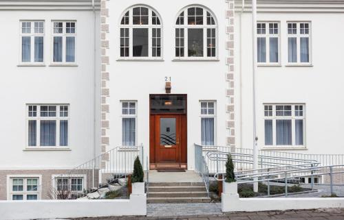 a white building with a brown door and stairs at Reykjavik Residence Apartment Hotel in Reykjavík