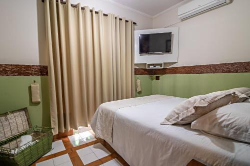 a bedroom with a bed and a tv on the wall at Pousada Estalagem de Brotas in Brotas