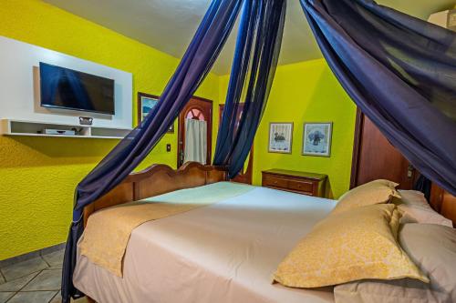 a bedroom with a bed with blue drapes at Pousada Estalagem de Brotas in Brotas