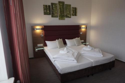 a bedroom with a bed with white sheets and pillows at Hotel und Restaurant Zum Deutschen Hause in Lübbenau