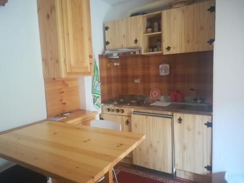 a kitchen with wooden cabinets and a wooden table at monolocale Sabrina in Torgnon
