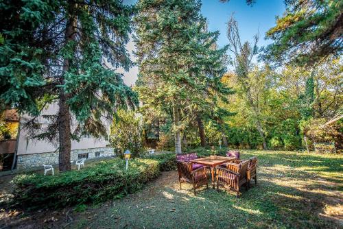 a table and chairs in a yard with trees at Korona Panzió Budapest in Budapest
