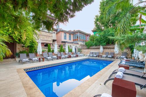 uma piscina com cadeiras e guarda-sóis em Tuvana Hotel em Antalya